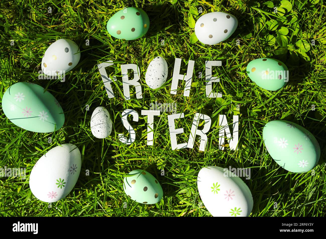Schriftzug Frohe Ostern und Ostereier auf dem Rasen Stock Photo