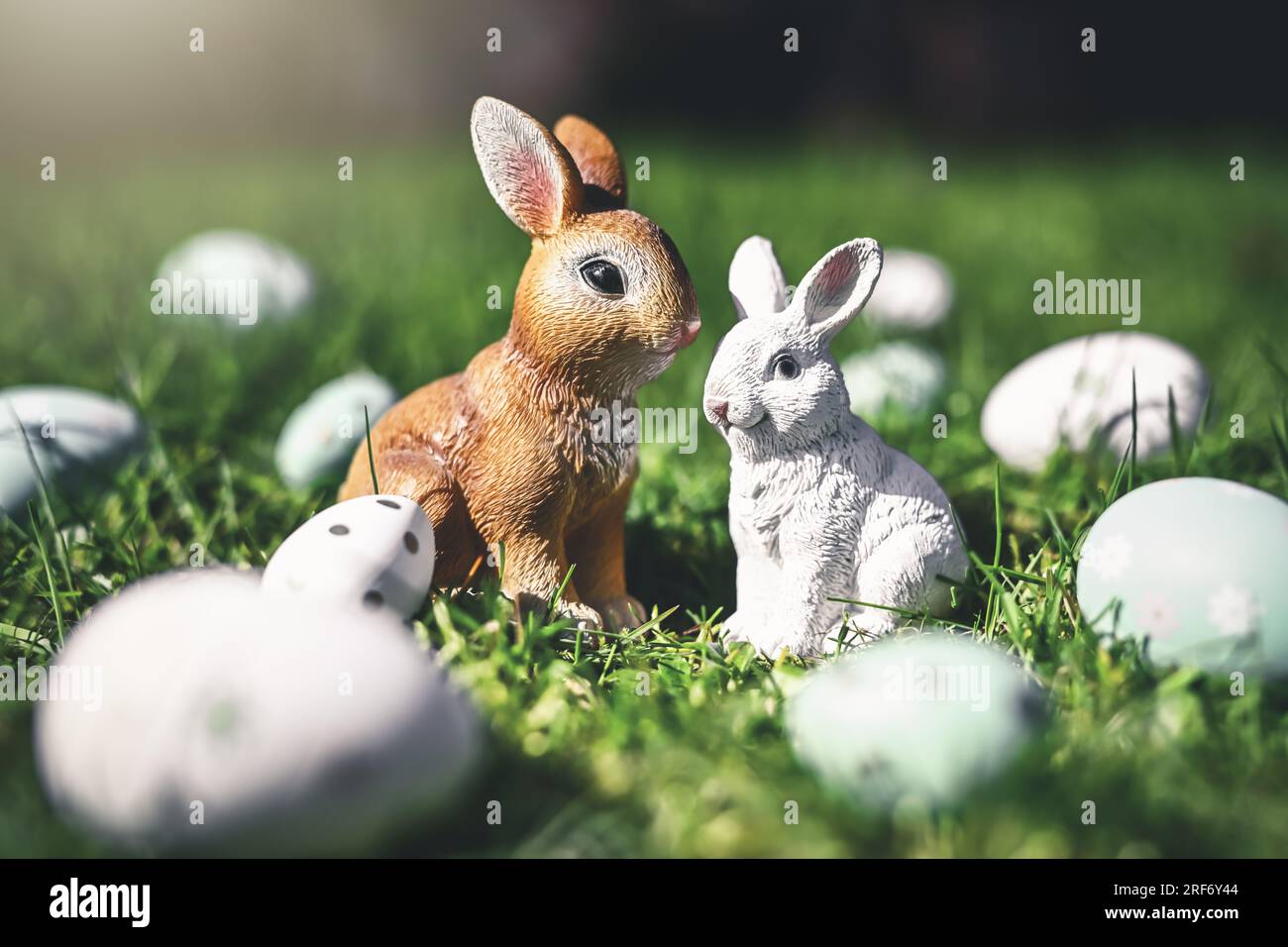 Osterhasenfiguren mit Ostereiern auf dem Rasen Stock Photo
