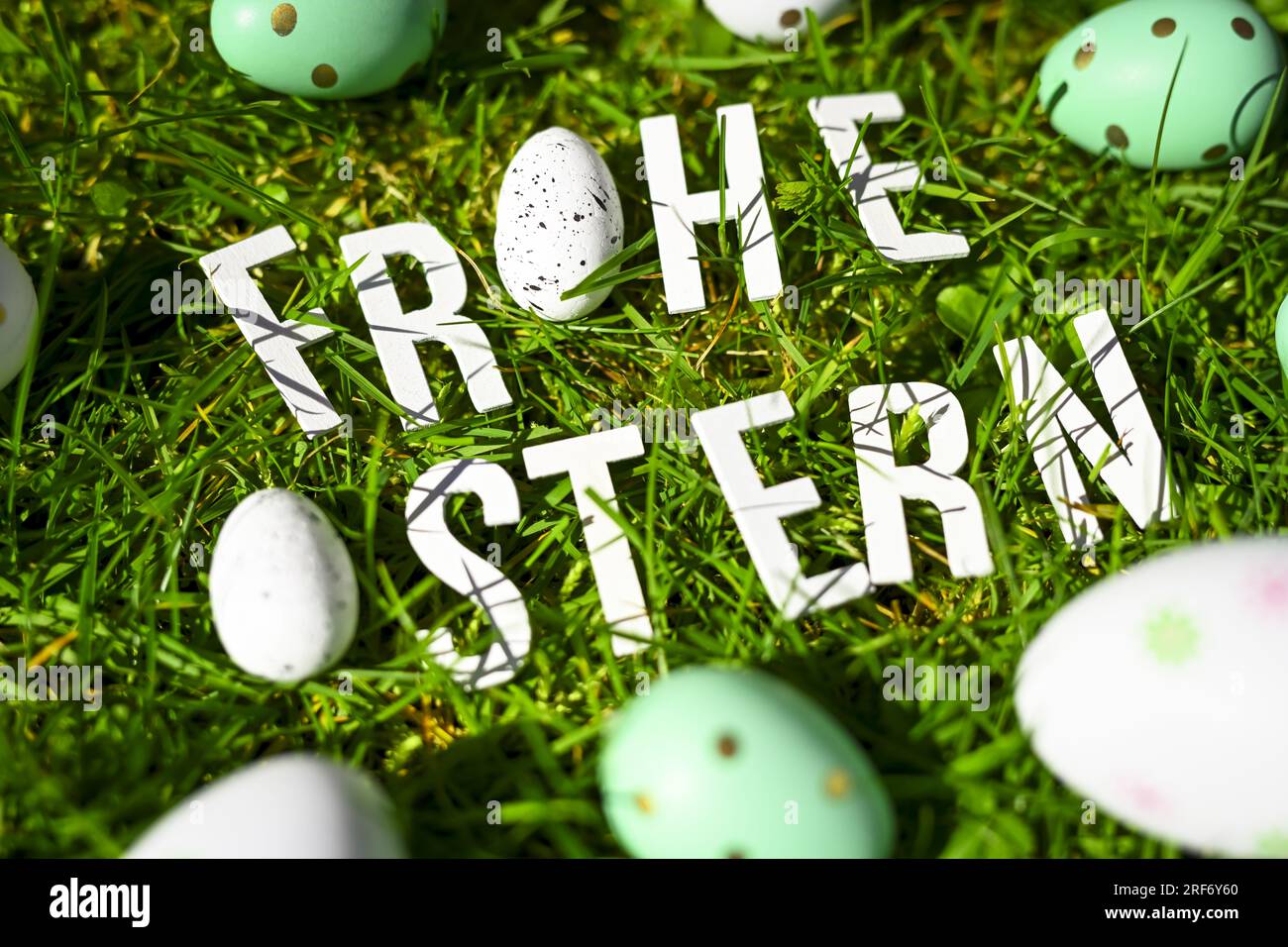 Schriftzug Frohe Ostern und Ostereier auf dem Rasen Stock Photo