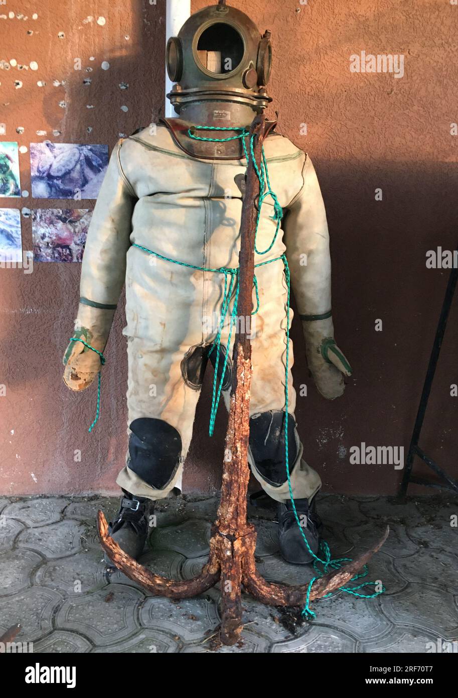 Anapa, Russia - June 16, 2023: Diving suit and helmet, old diving suit on the background of the wall in the seaport of Anapa. Stock Photo