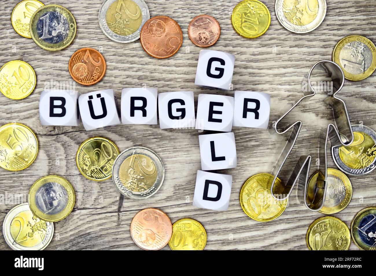 Würfelbuchstaben formen den Schriftzug Bürgergeld umgeben von Euromünzen Stock Photo