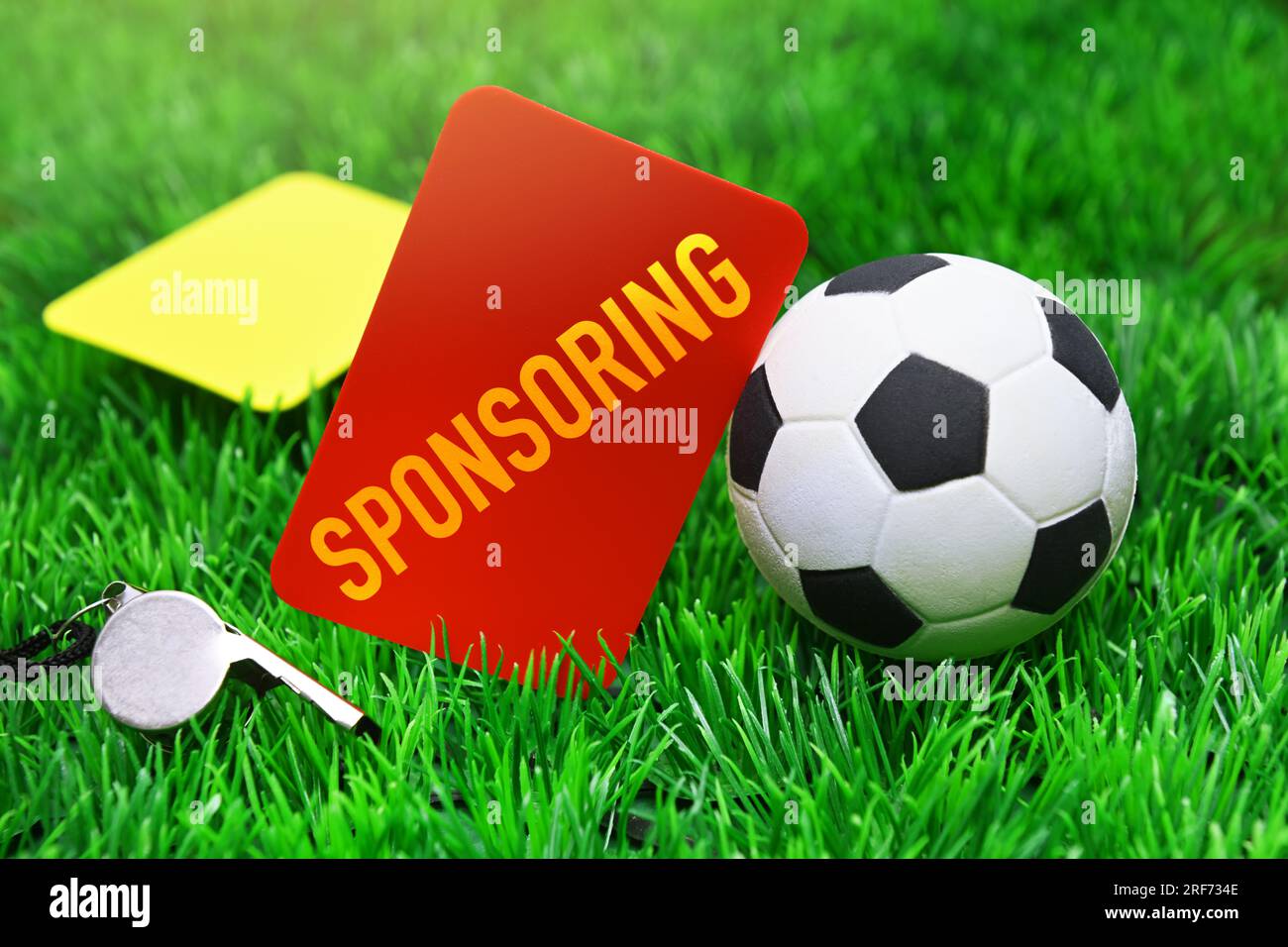 FOTOMONTAGE, Rote Karte mit Aufschrift Sponsoring neben Fußball auf Fußballrasen, Symbolfoto Kündigung von Sponsoring-Verträgen Stock Photo
