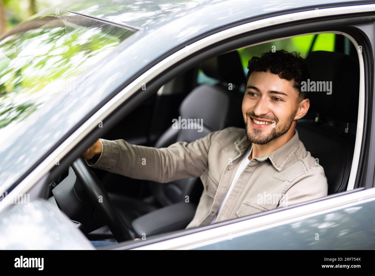 Profile view of handsome young man driving his car on city street Stock Photo