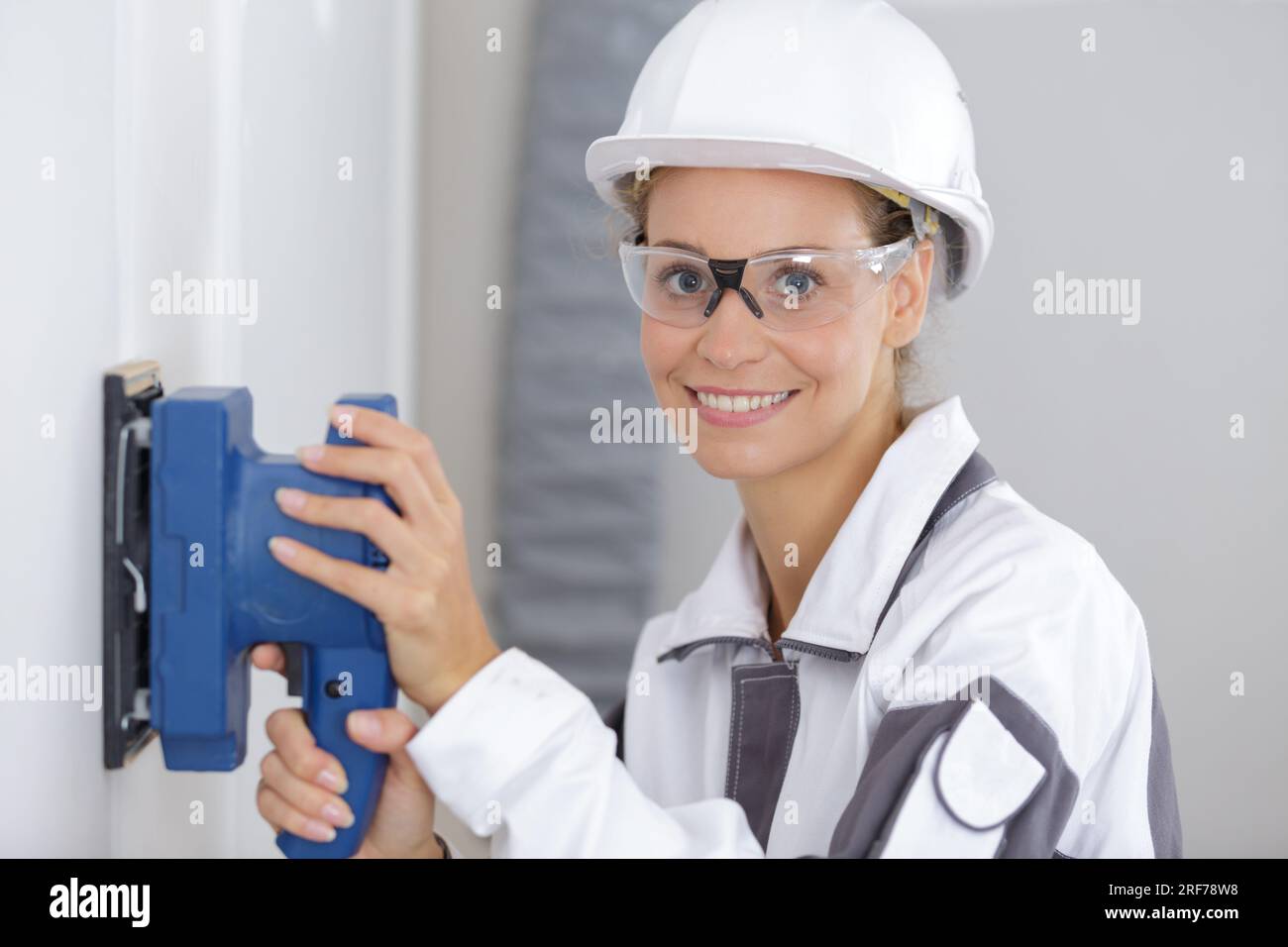 female construction worker smoothing wall surface Stock Photo