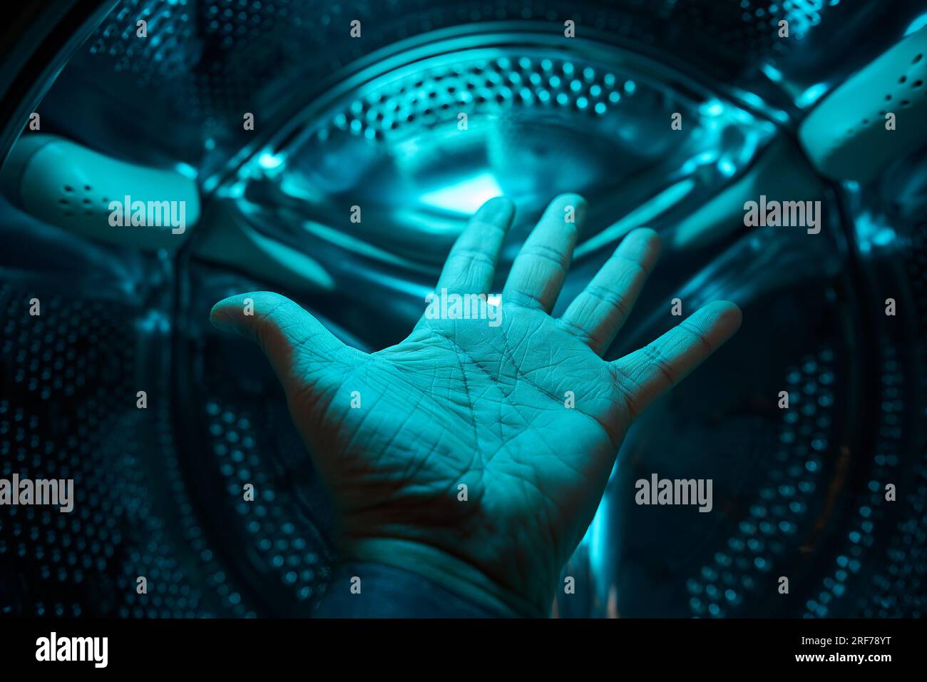 A Hand inside washer in a blue light, future, sci-fi, concept Stock Photo