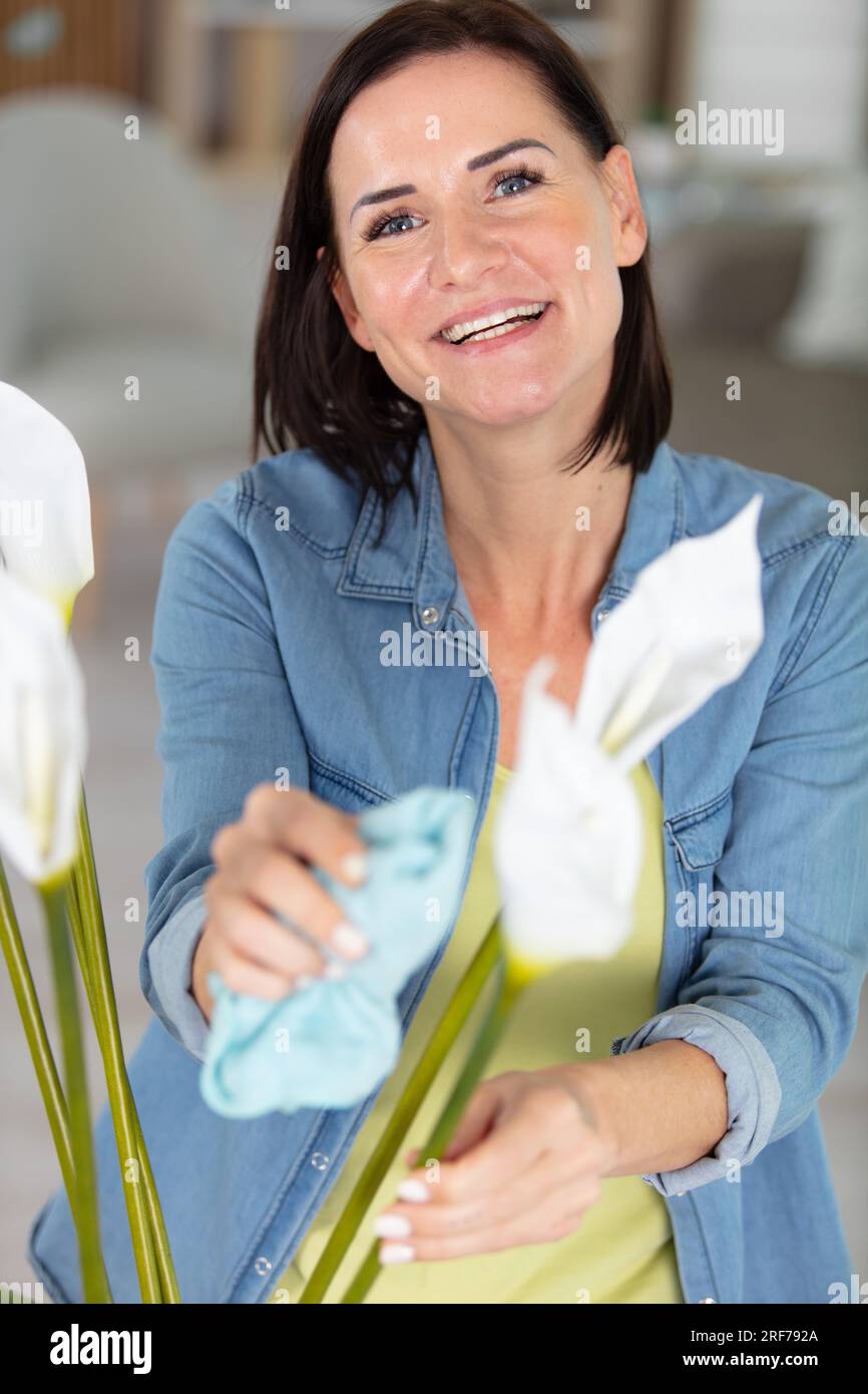 young businesswoman dusts plants in flowerpots Stock Photo