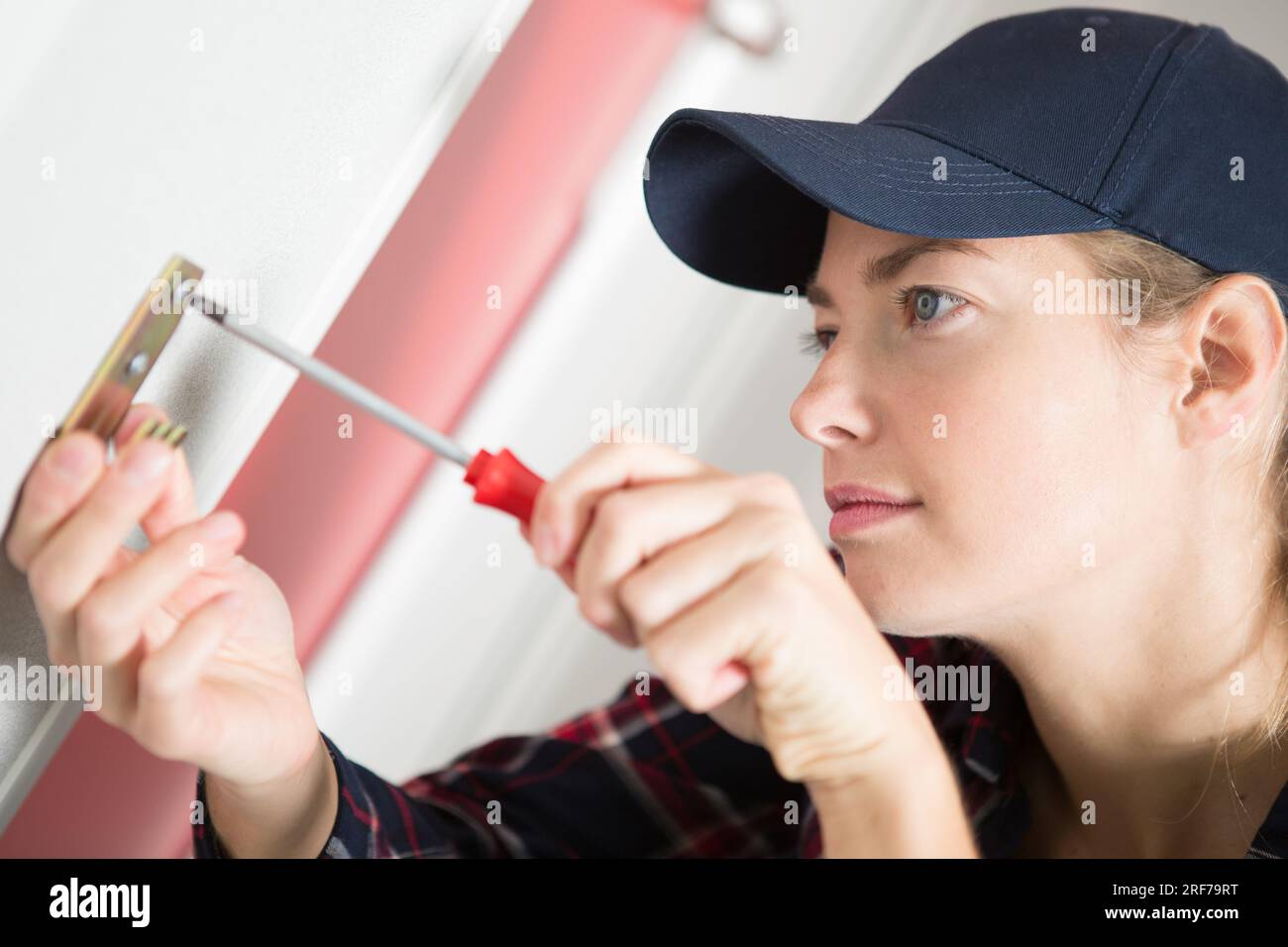 female handyman installing a hook on the wall Stock Photo Alamy
