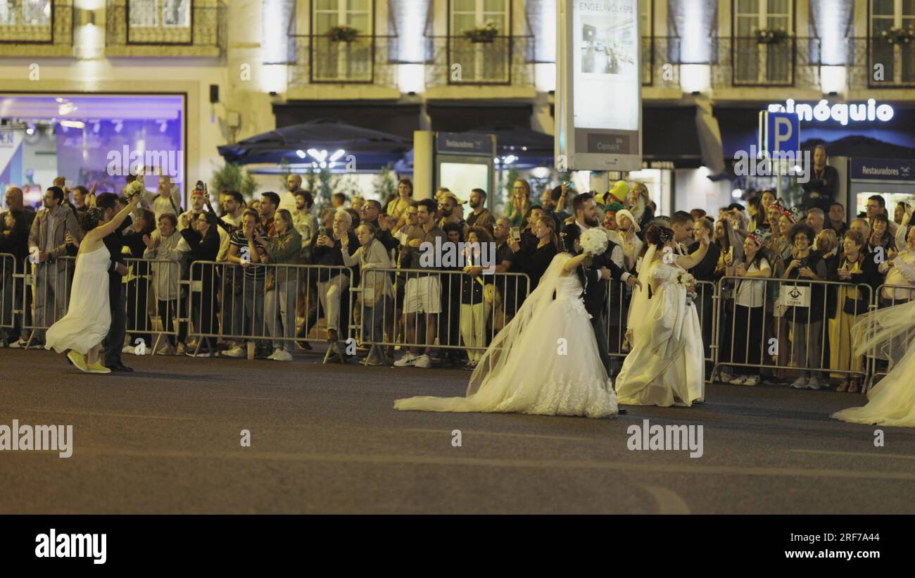 12 june 2023 Rua da Liberdade, Lisbon Portugal - Santo Antonio Festival - parade of brides - women walking down the road in white dresses. Mid shot Stock Photo