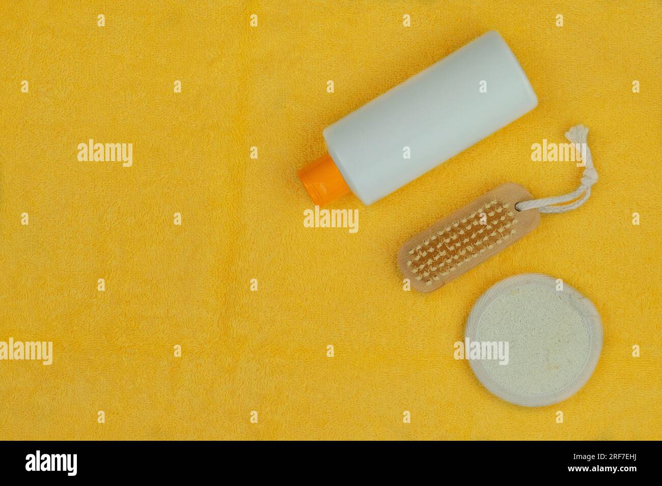 Washcloths, shampoo and cotton sponge in yellow background. Wash and spa. Top view. Stock Photo