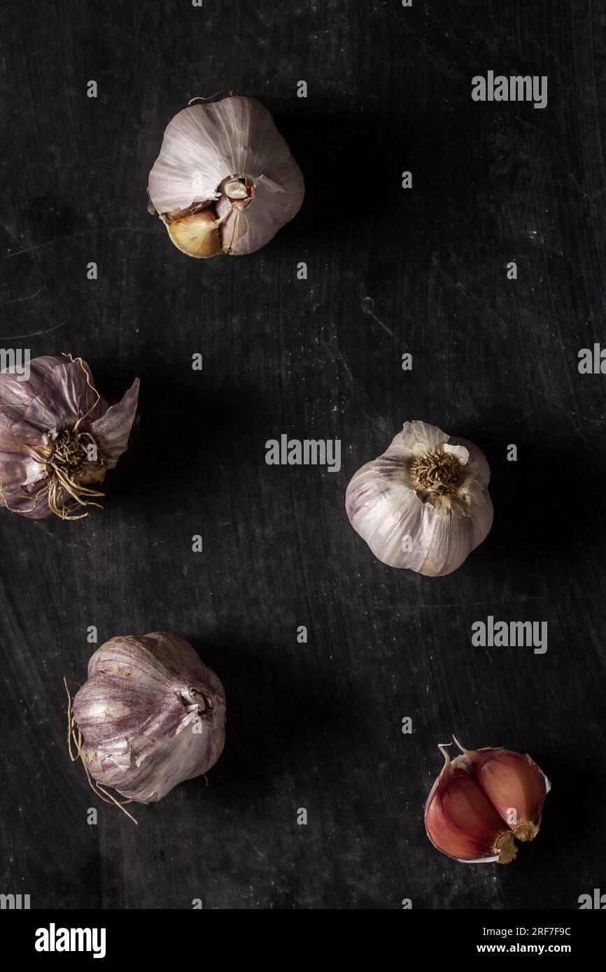 Fresh garlic bulbs and cloves grouped on black background. Flat lay ...