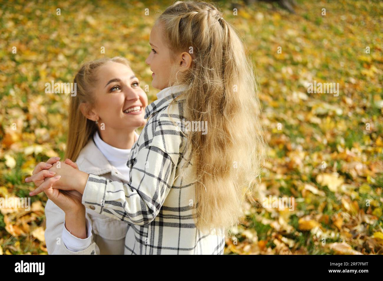 Mother and daughter spend time together in the autumn park. Mother ...