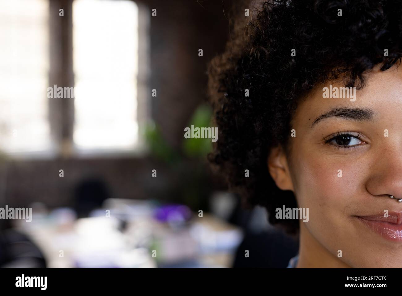 Half face portrait of a biracial woman smiling at office with copy space Stock Photo