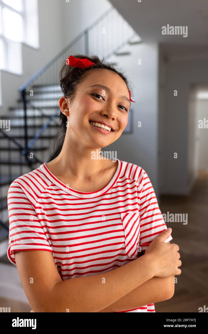 Portrait of happy asian woman with red band on head and arms crossed at home Stock Photo