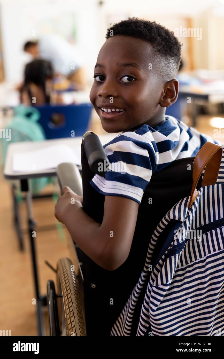 Portrait of happy african american school boy sitting in wheelchair in ...