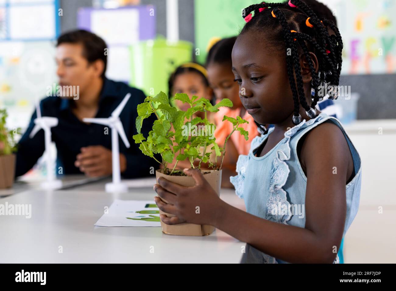 Happy african american girl with plant in ecology class at elementary school Stock Photo