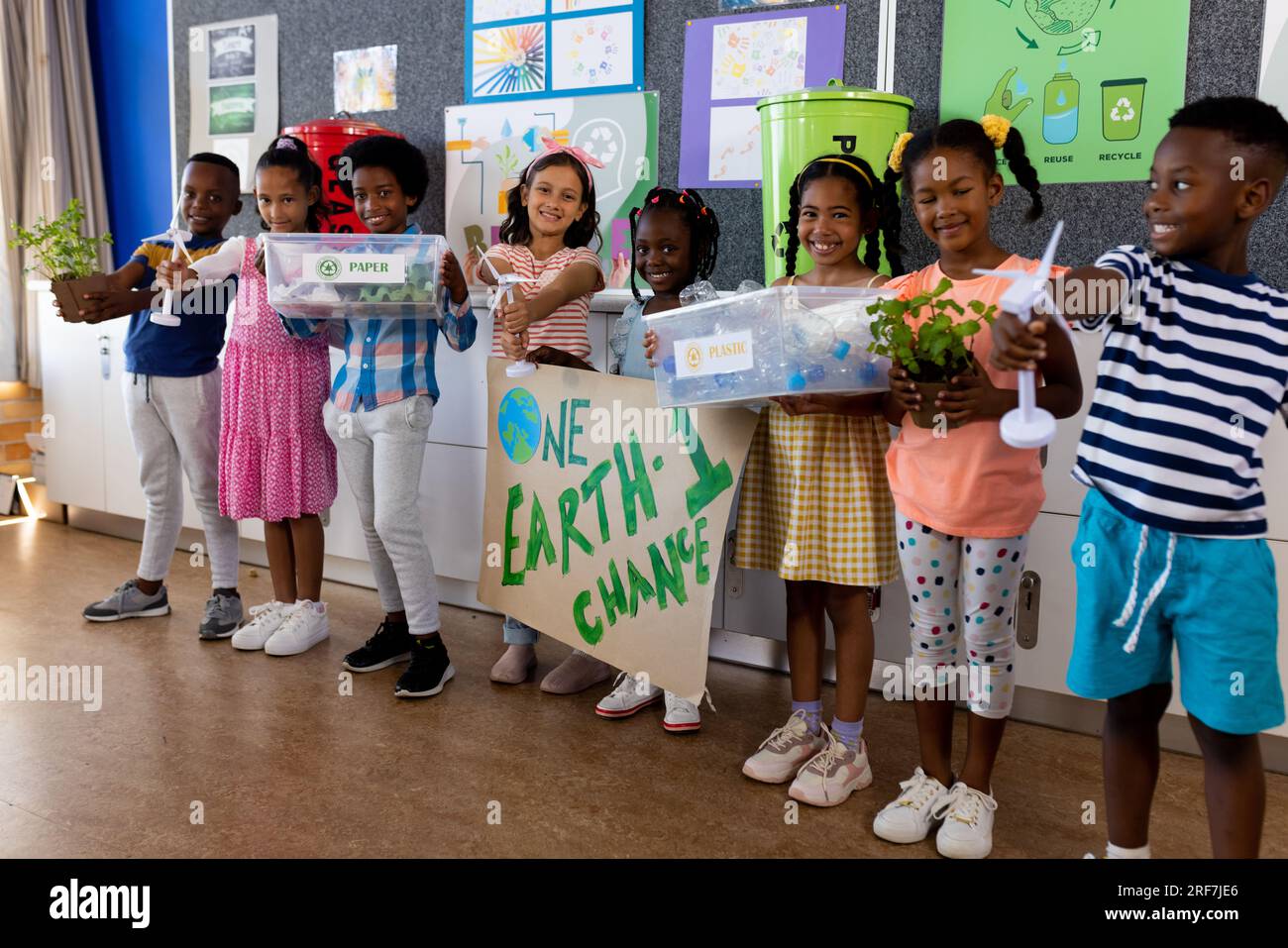Portrait of happy diverse children with ecology items and plants in class at elementary school Stock Photo