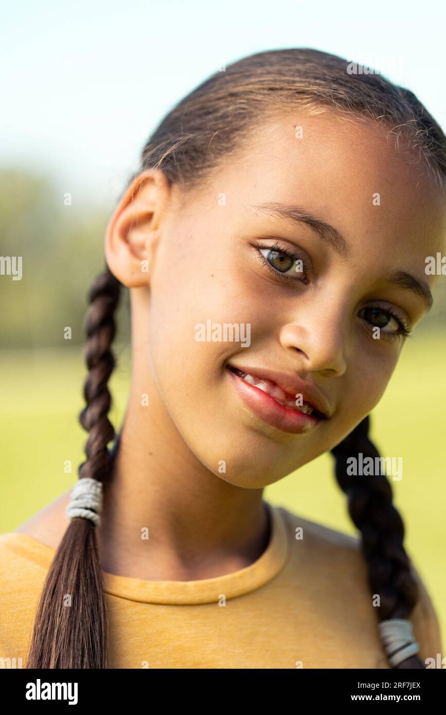 Portrait of biracial schoolgirl smiling in sports field at elementary school Stock Photo