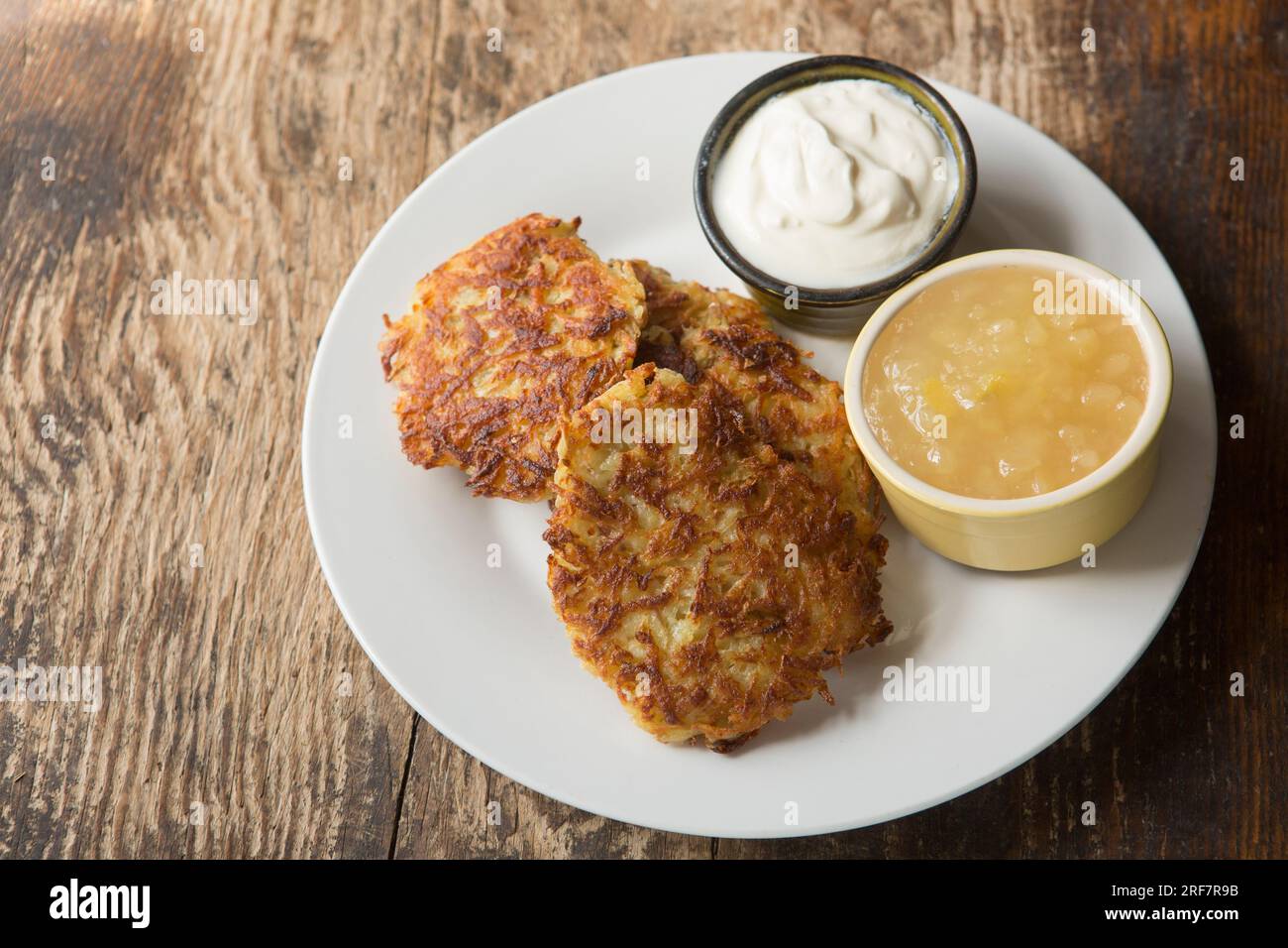 Homemade Polish potato pancakes made from grated potato, flour, egg and onion that have been fried in oil. Served with soured cream and apple sauce. E Stock Photo