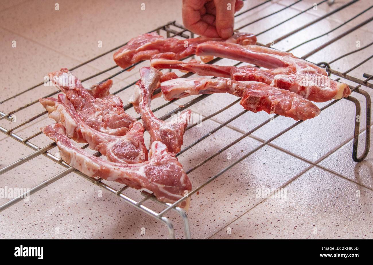woman's hand placing lamb chops on a grill seasoned with salt and ...