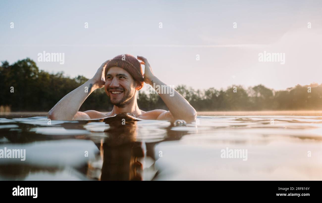 Young man soaks in the winter lake at morning. Male person taking care of his health Stock Photo