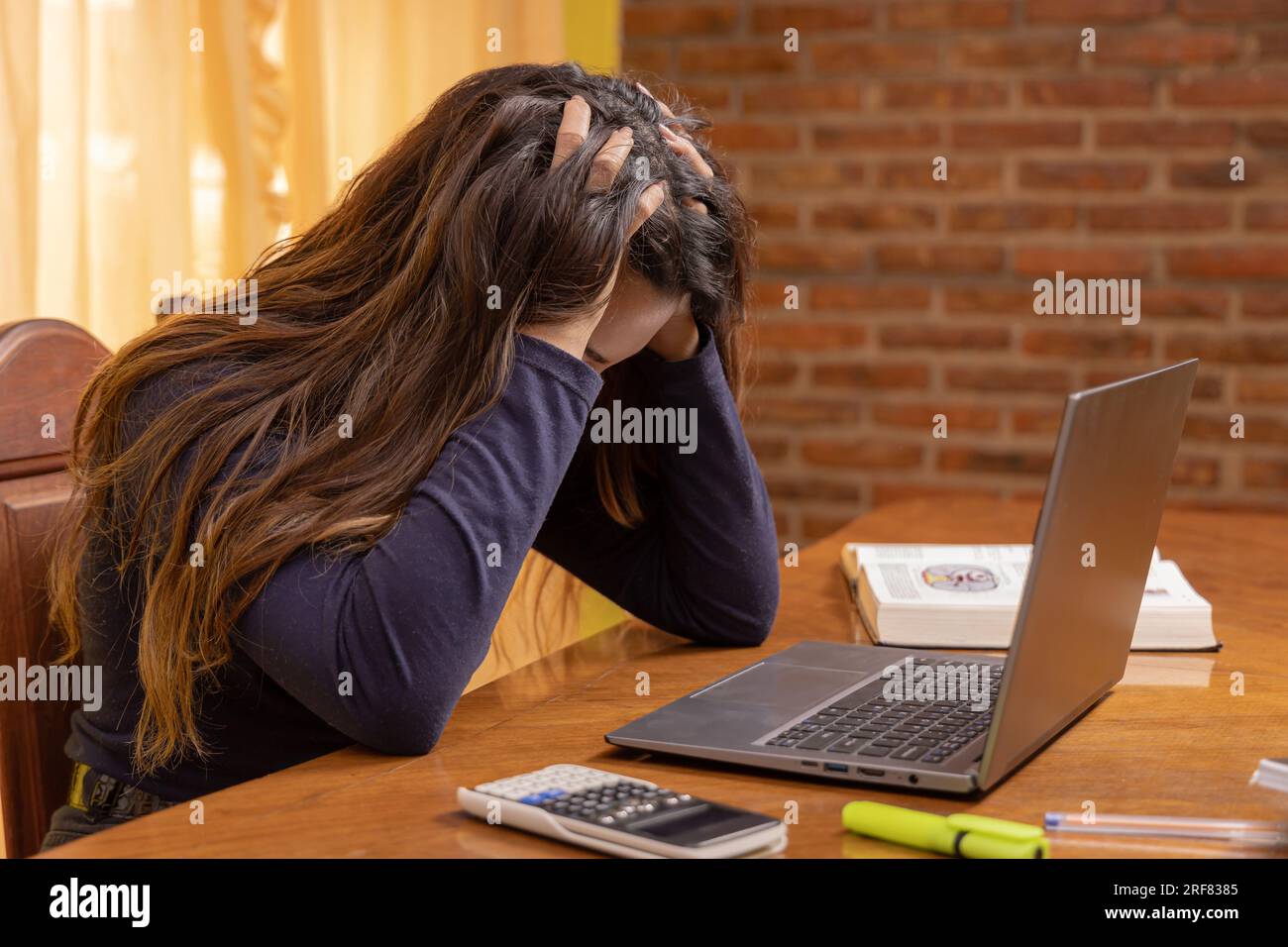 Stressed latin girl, studying in front of a laptop. Stock Photo