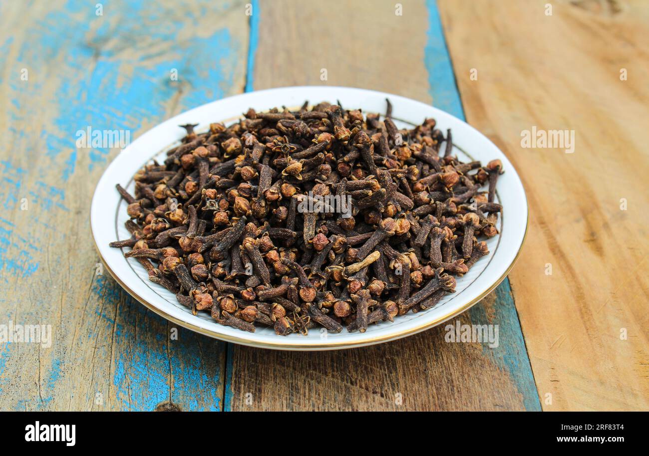 Dried Cloves in a plate on wooden background Stock Photo