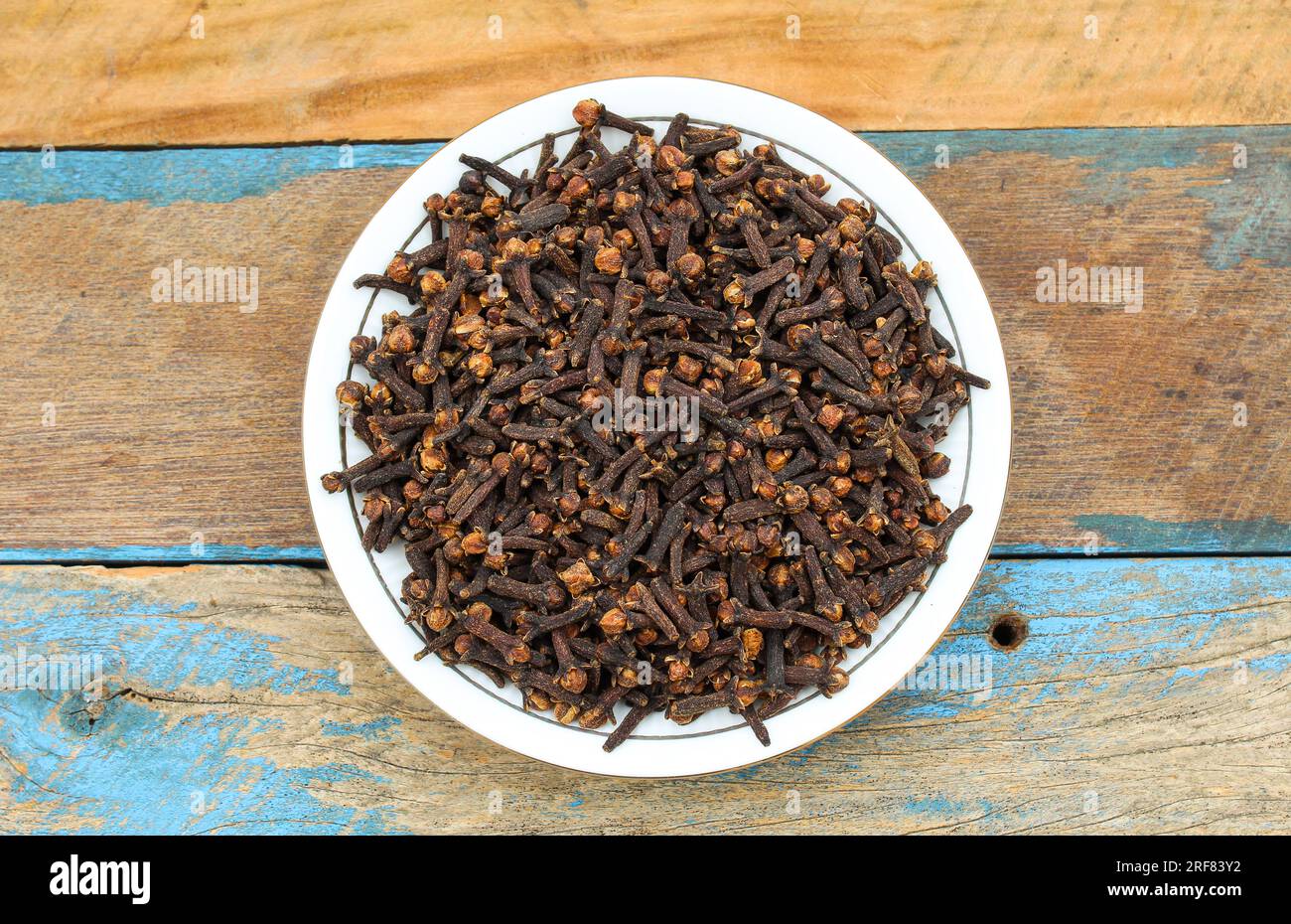 Dried Cloves in a plate on wooden background top view Stock Photo