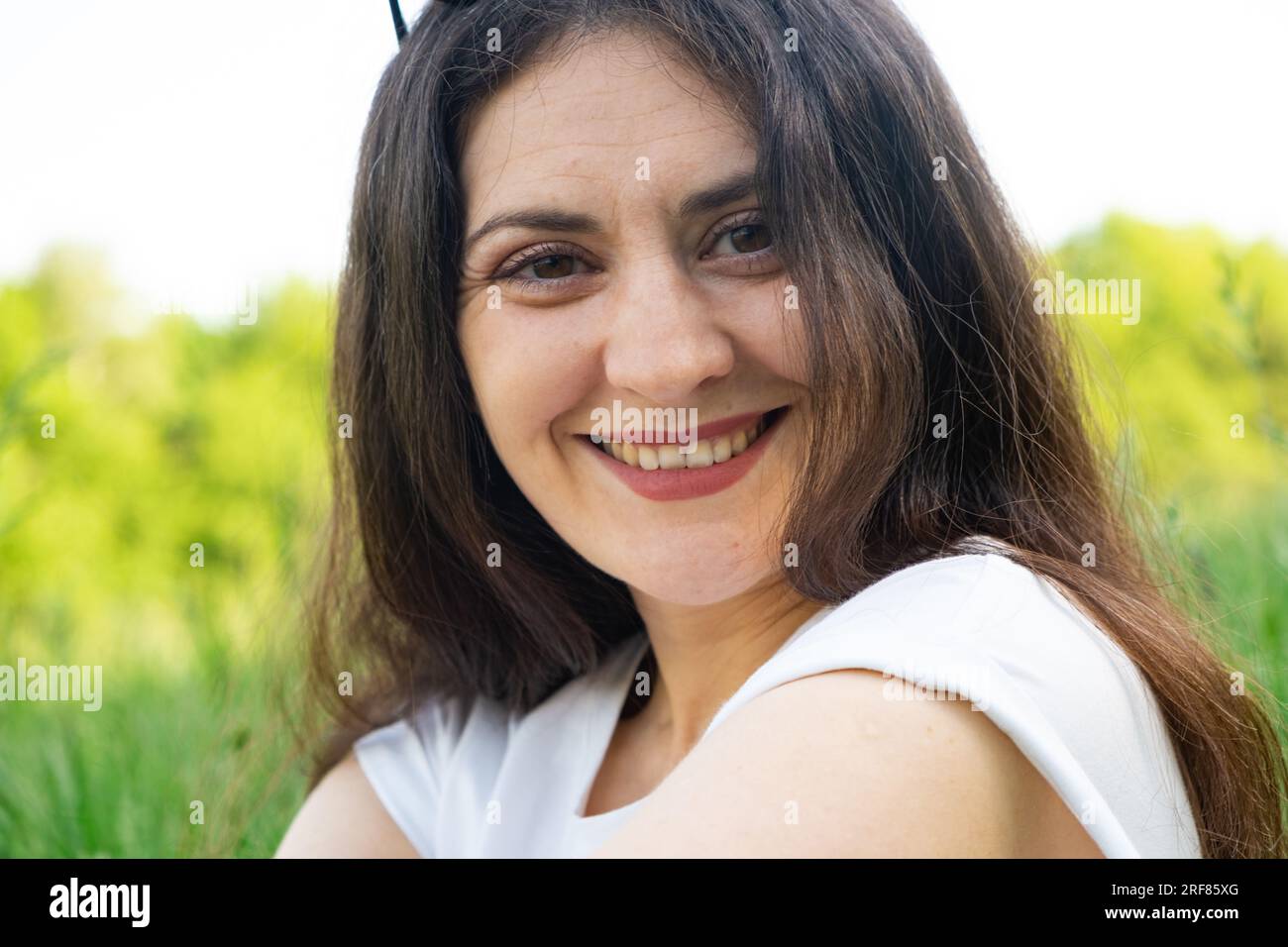 Portrait of a 35-year-old brunette woman looking at the camera smiling ...