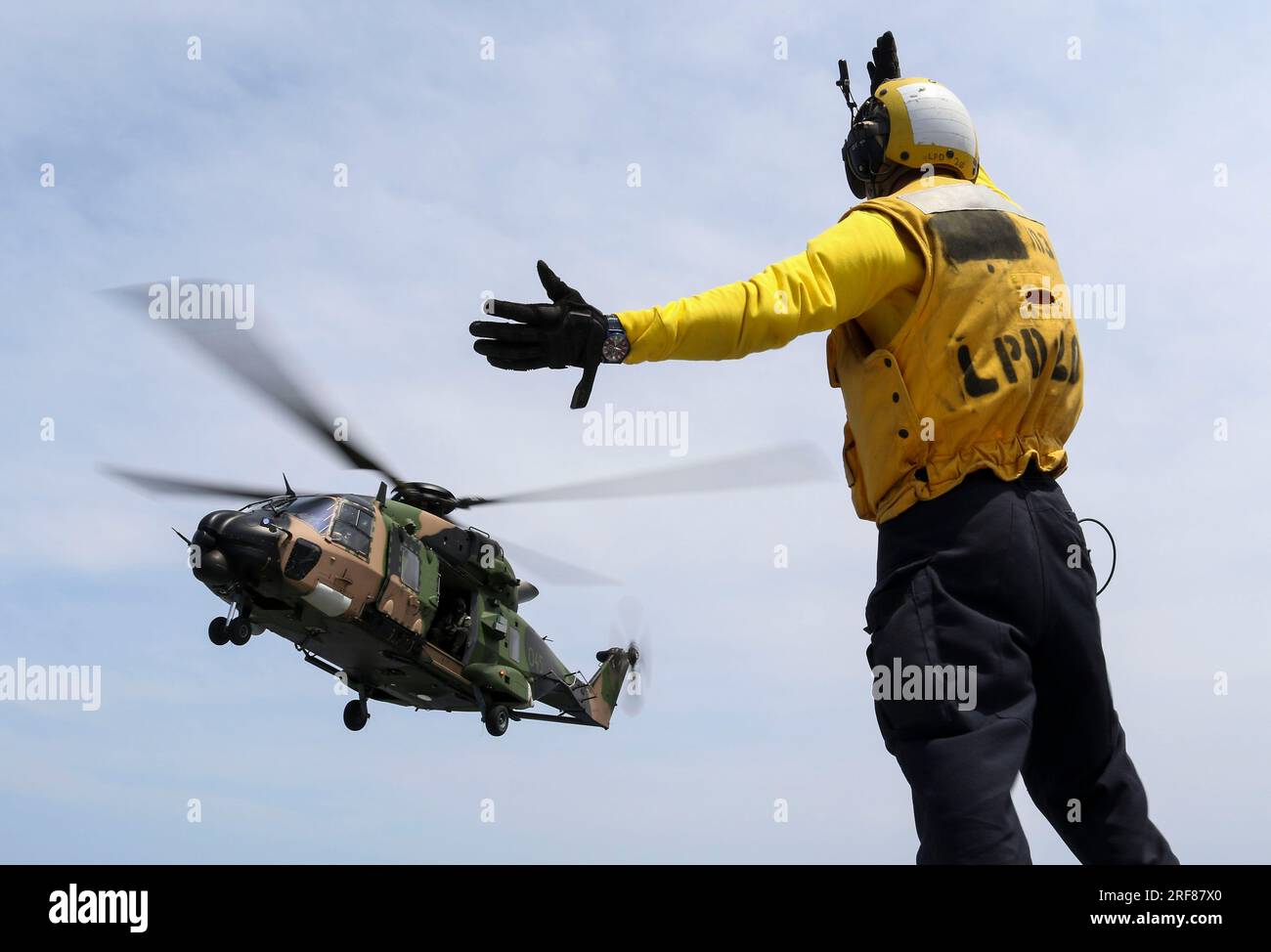 Coral Sea, Australia. 19 November, 2018. U.S Navy sailor Caleb Brawner, signals a Royal Australian Navy MRH-90 Taipan helicopter, for take off from the flight deck of the San Antonio-class amphibious transport dock USS Green Bay during cross deck flight operations, November 19, 2018 on the Coral Sea.  Credit: MC2 Anaid Banuelos Rodriguez/US Navy Photo/Alamy Live News Stock Photo