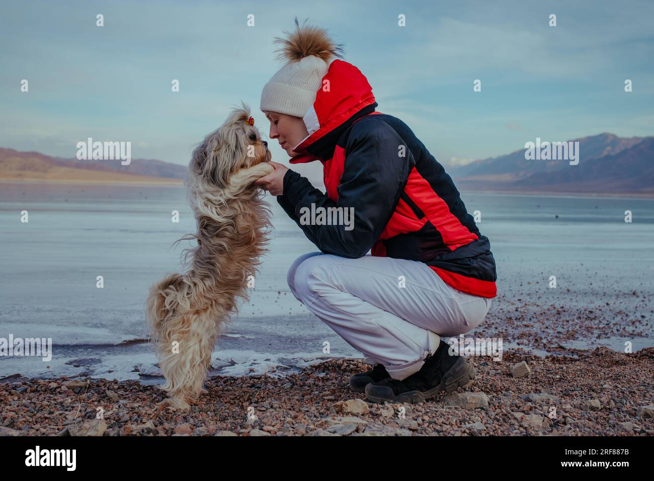 Young woman tourist with dog posing on frozen lake background at winter Stock Photo