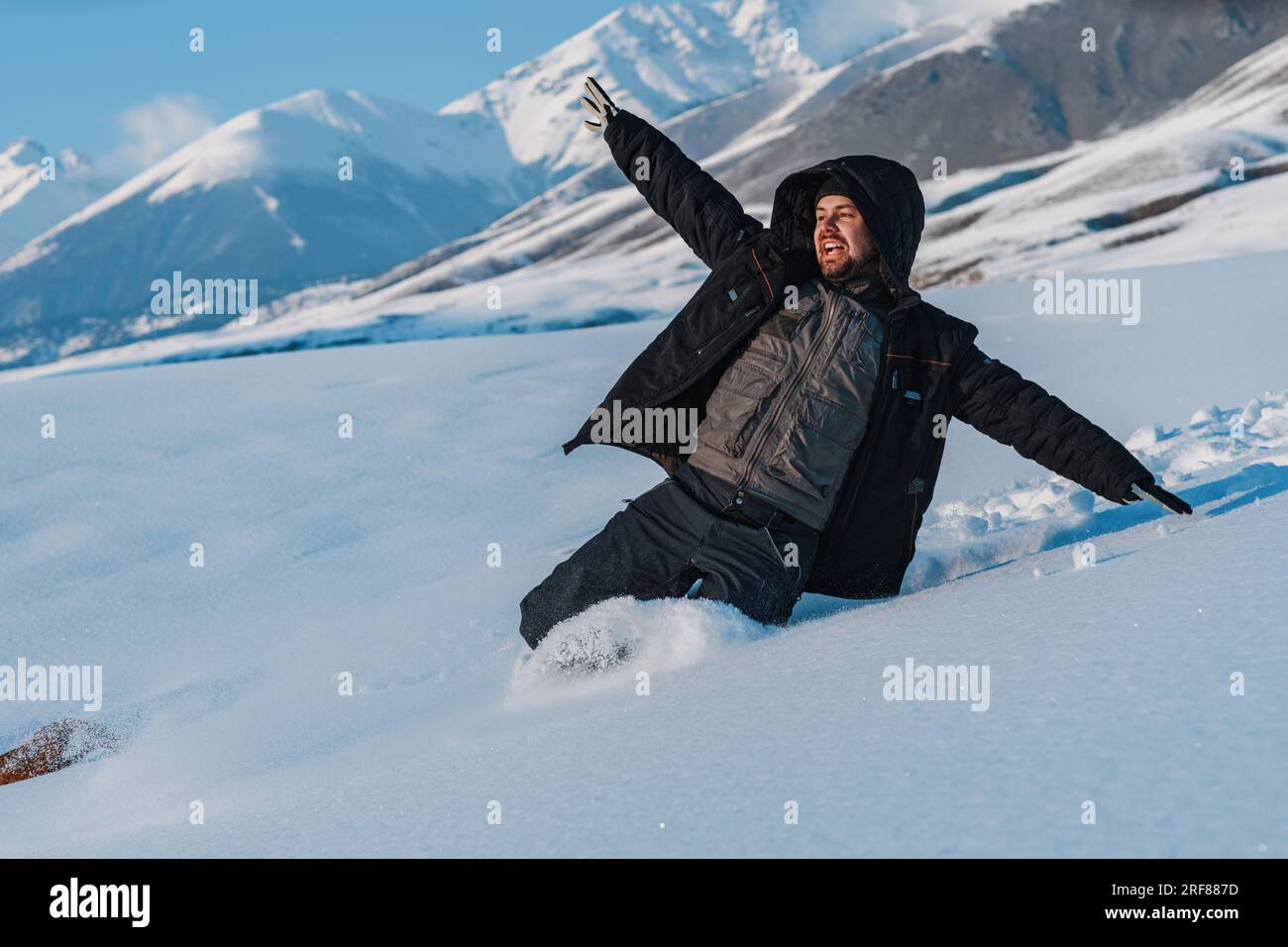 Young man tourist sliding down from mountain at winter season Stock Photo