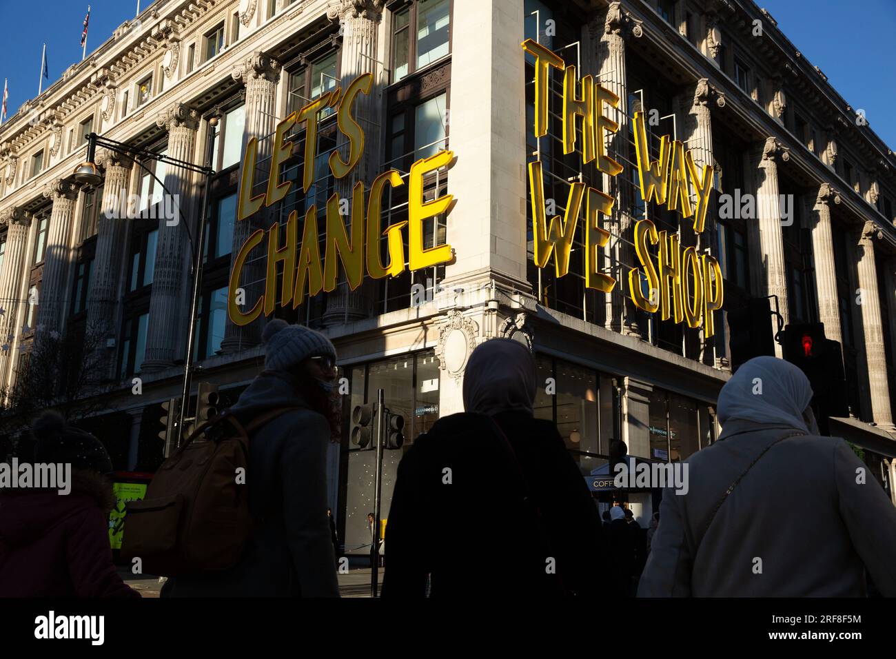 People are silhouetted against Selfridges store on Oxford Street in
