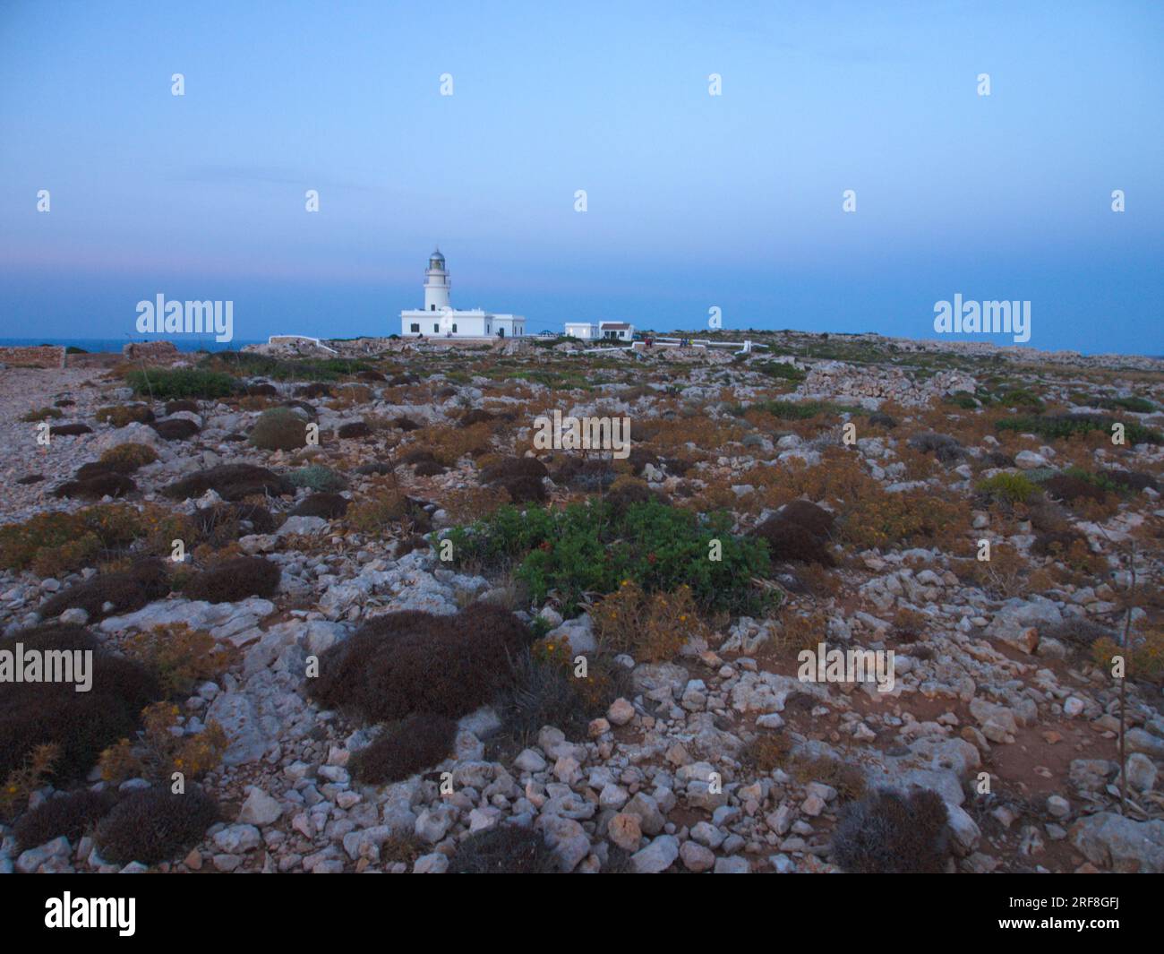 A lighthouse on the Island of Menorca surrounded by stony ground.  Un faro de la Isla de Menorca  rodeado de un terreno pedregoso. Stock Photo