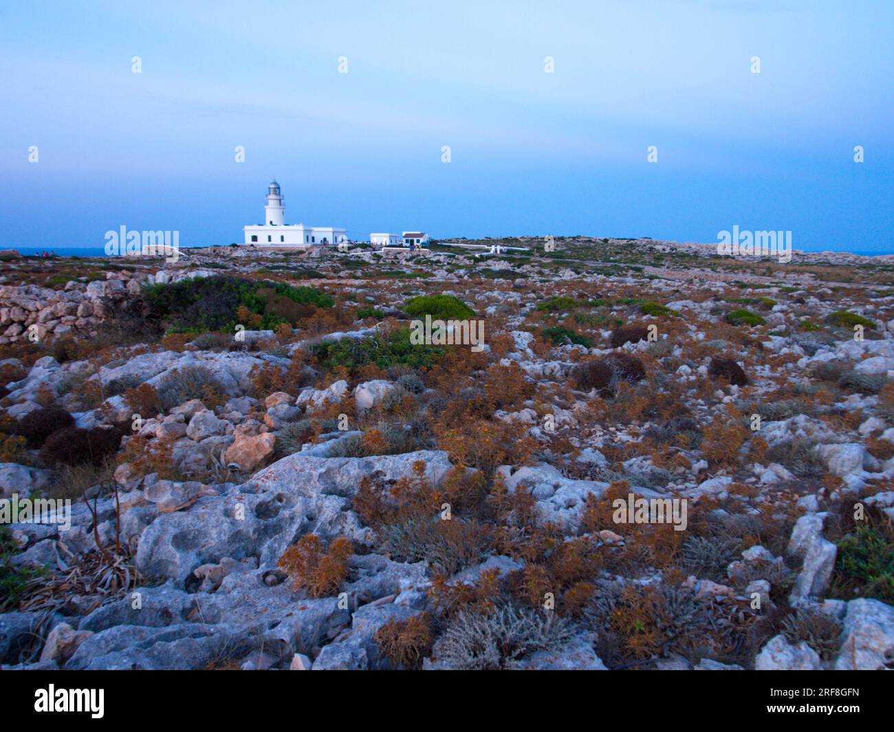 A lighthouse on the Island of Menorca surrounded by stony ground.  Un faro de la Isla de Menorca  rodeado de un terreno pedregoso. Stock Photo