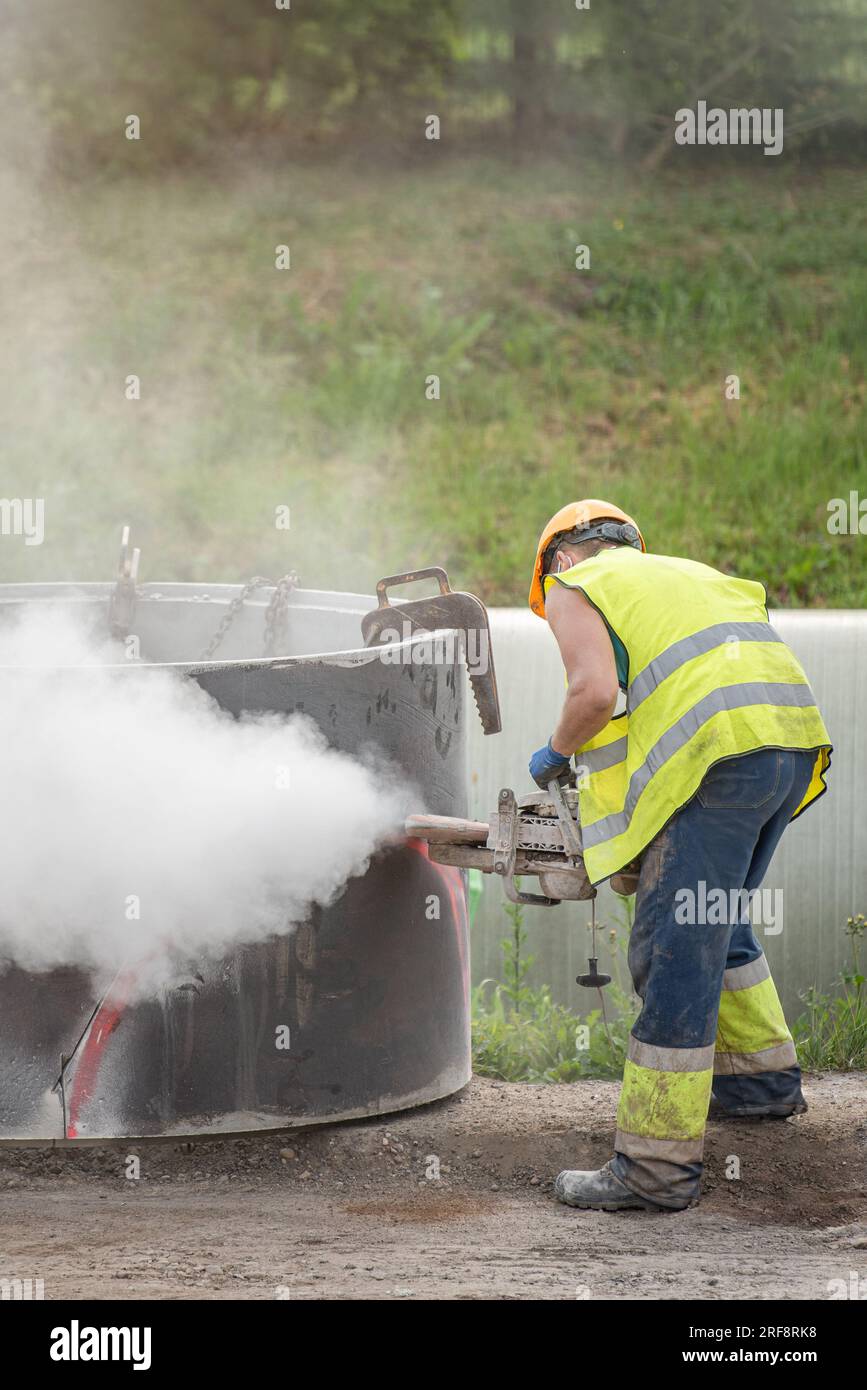A worker cuts concrete with a special saw. The process of cutting a