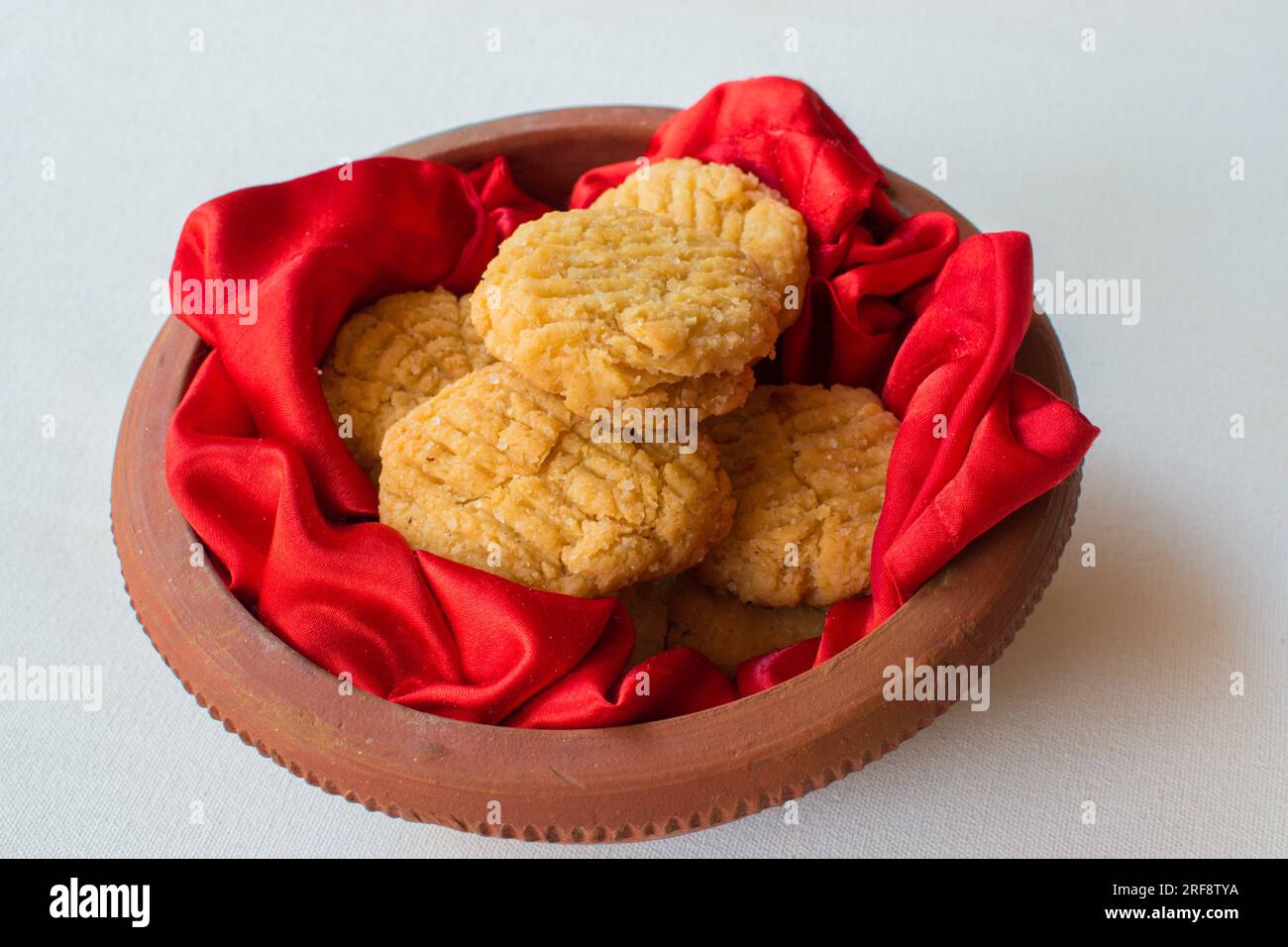 Thekua , an Indian sweet dish or snack in earthen pot with beautiful red and white background. Popular in bihar jharkhand. Prashad in chhath maha parv Stock Photo