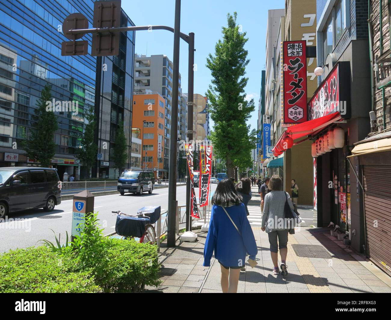 Modern Japan: view of a street scene in the Tokyo metropolis with tall buildings and pedestrians walking along the pavement. Stock Photo