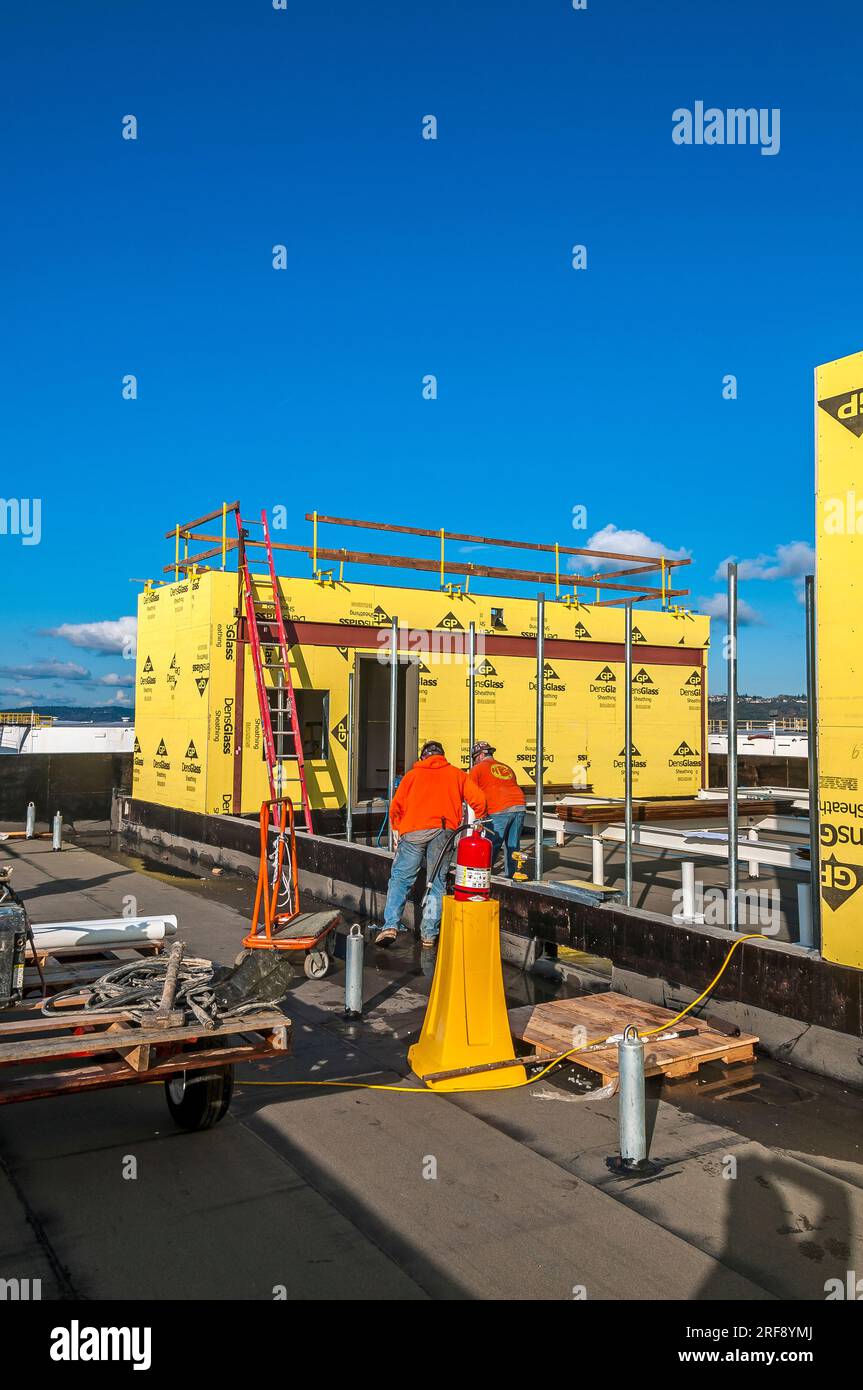 Two construction workers in hardhats and safety vests performing their
