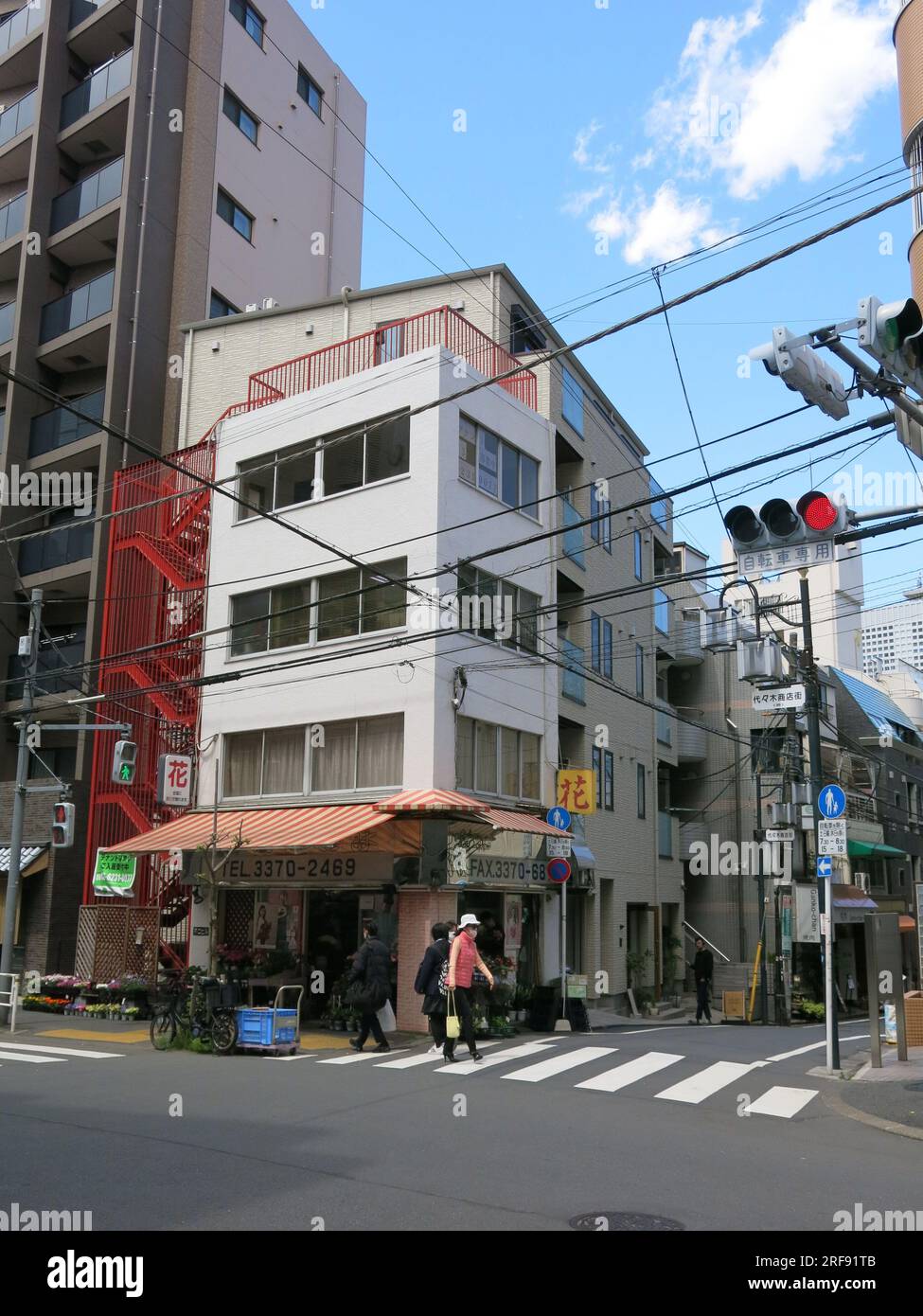 Street scene in Yoyogi, a suburb of wider Tokyo, showing a commercial district with tall buildings, pedestrian crossings & power lines across the road. Stock Photo