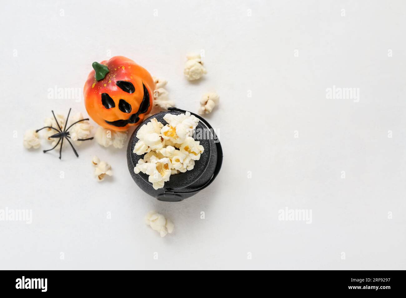 Bowl with tasty popcorn, pumpkin and spider on white background ...
