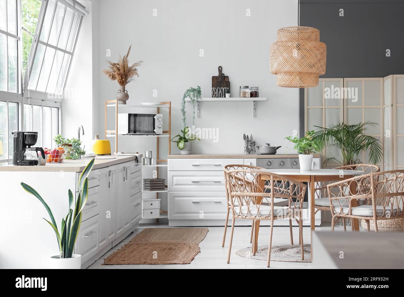 Interior of light kitchen with white counters, dining table and big ...
