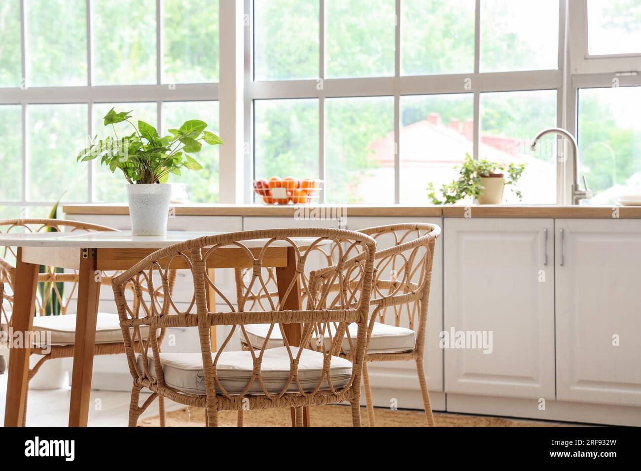 Interior of light kitchen with white counters, dining table and big ...