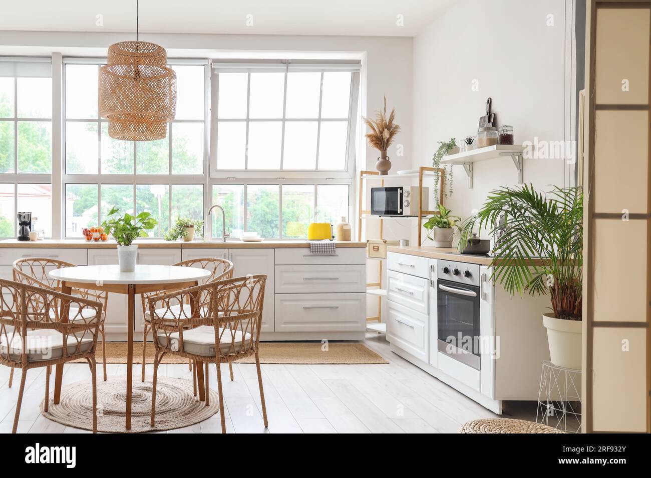 Interior of light kitchen with white counters, dining table and big ...