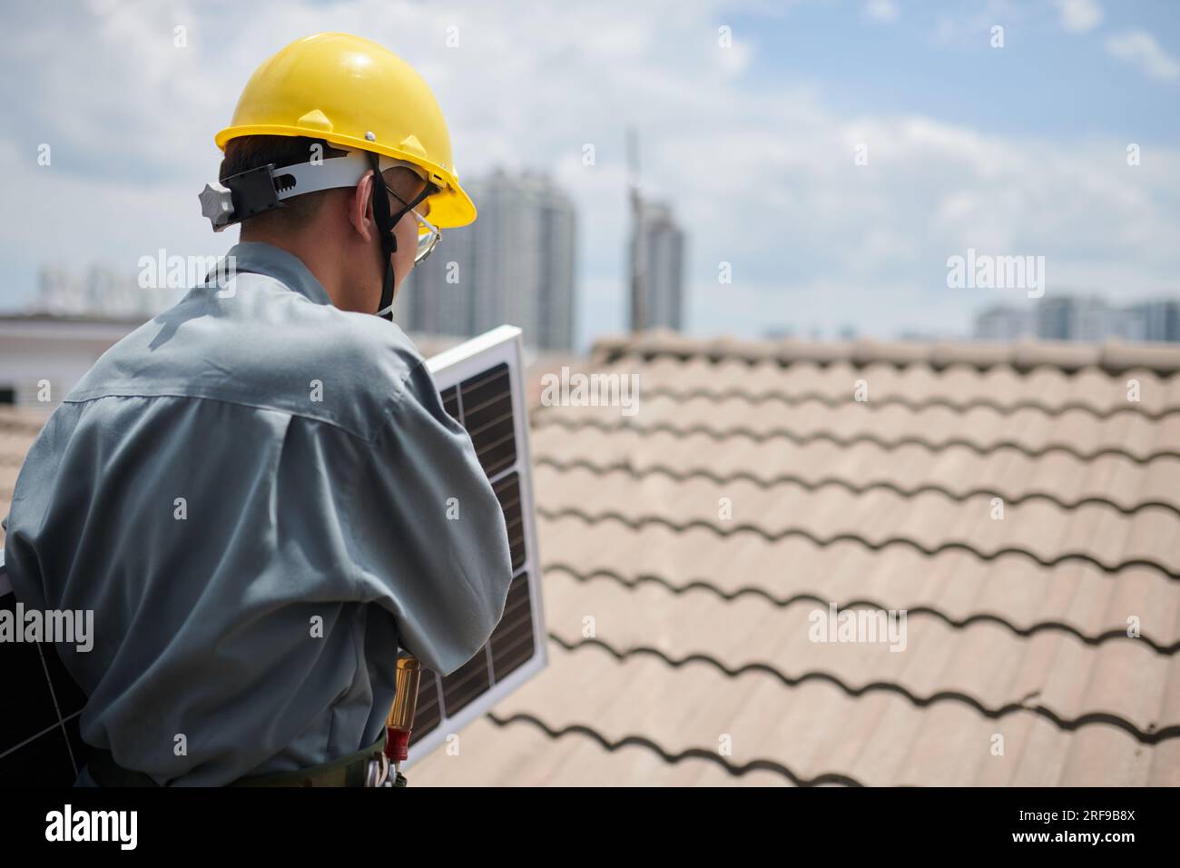 Contractor carrying solar panel, when walking on roof Stock Photo