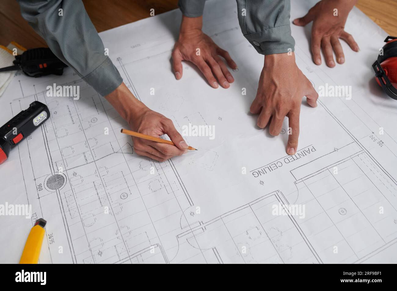 Hands of builders checking construction plan before starting work, view from above Stock Photo