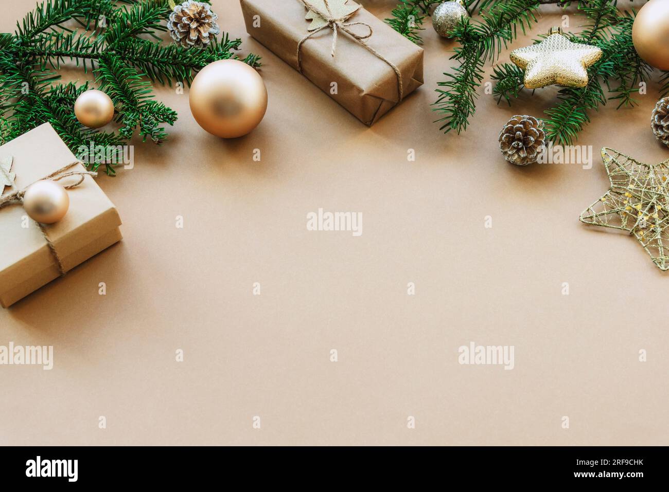 Festive Christmas background with spruce twigs, gift boxes and baubles on beige table. Top view, flat lay, copy space. Stock Photo