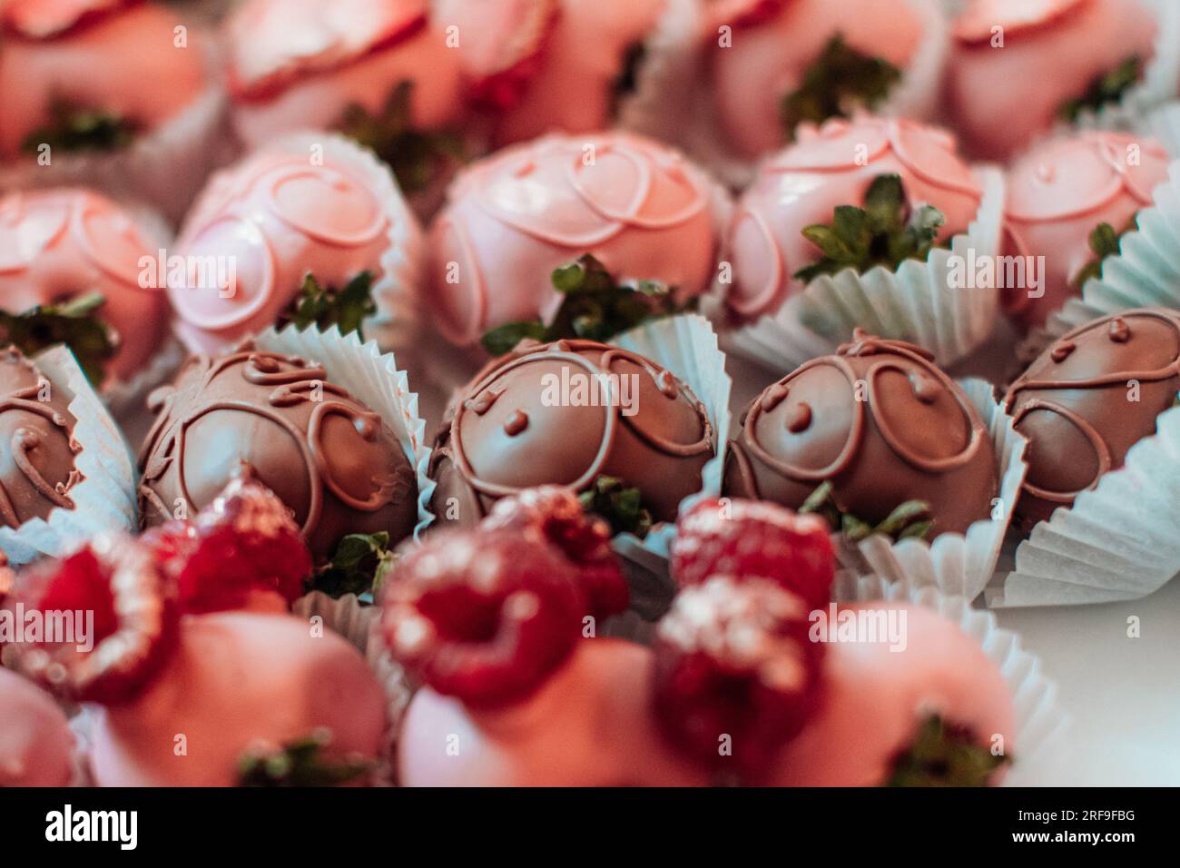 Pink chocolate covered strawberries with fresh raspberries on top. Candies and sweets collection. Tasty set for holidays Stock Photo