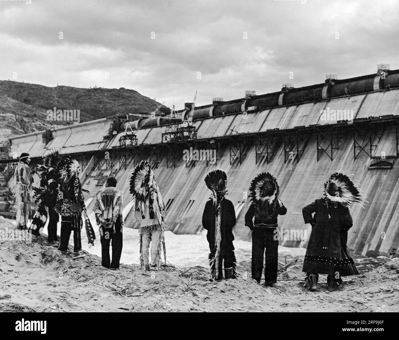 Grand Coulee Dam; Washington; c 1941  Native American watching the final stages of construction on the Grand Coulee Dam on the Columbia River, their traditional fishing ground, in Washington. It is the largest electric power producing facility in the US. It was built as part of the Works Progress Administration. Stock Photo