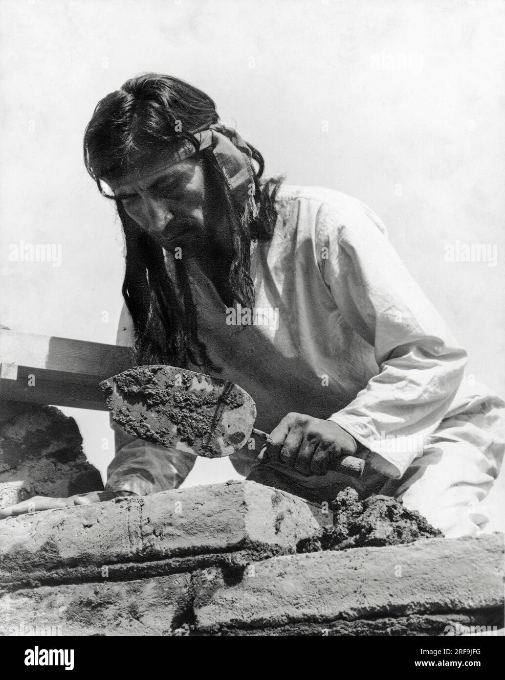 California:  c. 1930  The padres taught the Native Americans to make the adobe bricks used in the building of the missions. After they were made and dried, the building of the walls was started. Each brick was forced into place in the soft mortar. The Indians were taught to set each brick carefully in order to keep the layers of brick level and to form straight walls Stock Photo