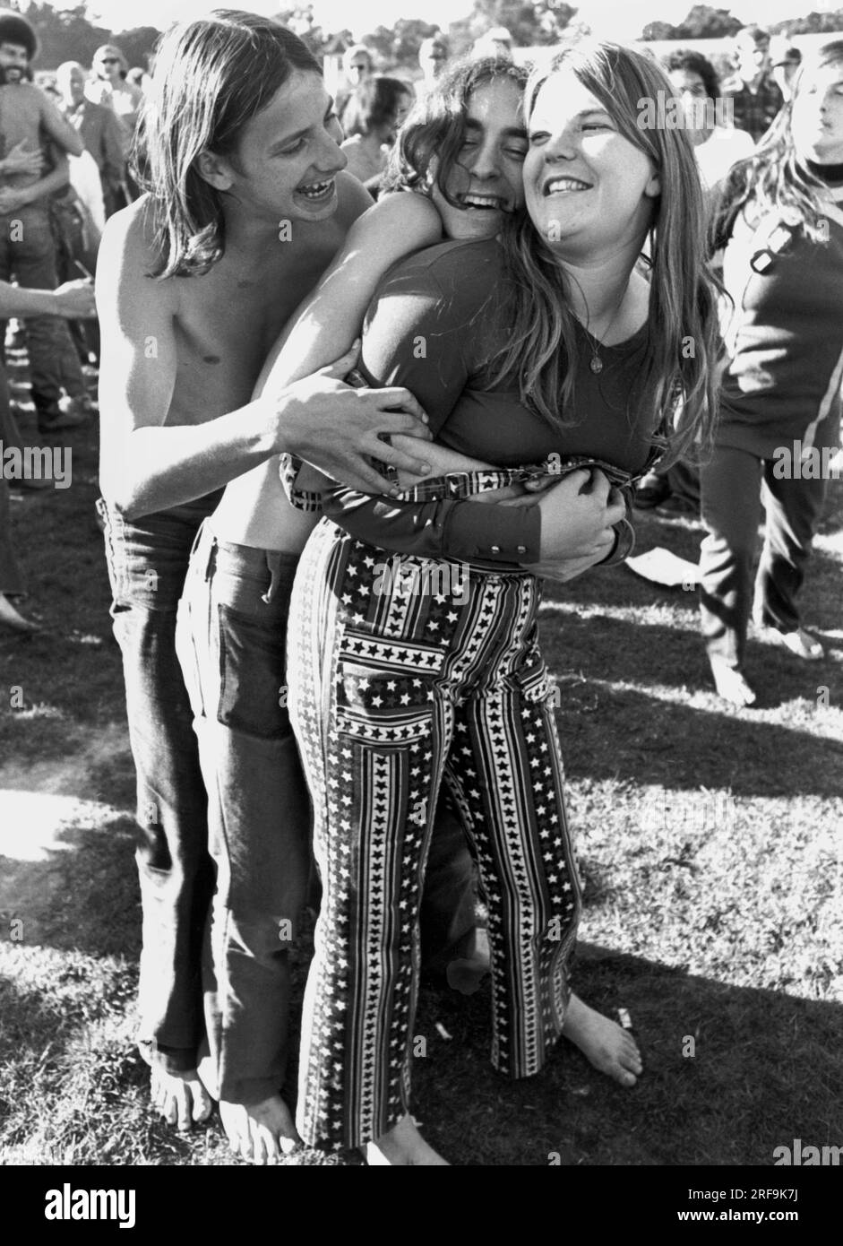 San Francisco, California:  c. 1969 Three barefoot flower children engage in a group hug at a lovein in Golden Gate Park Stock Photo